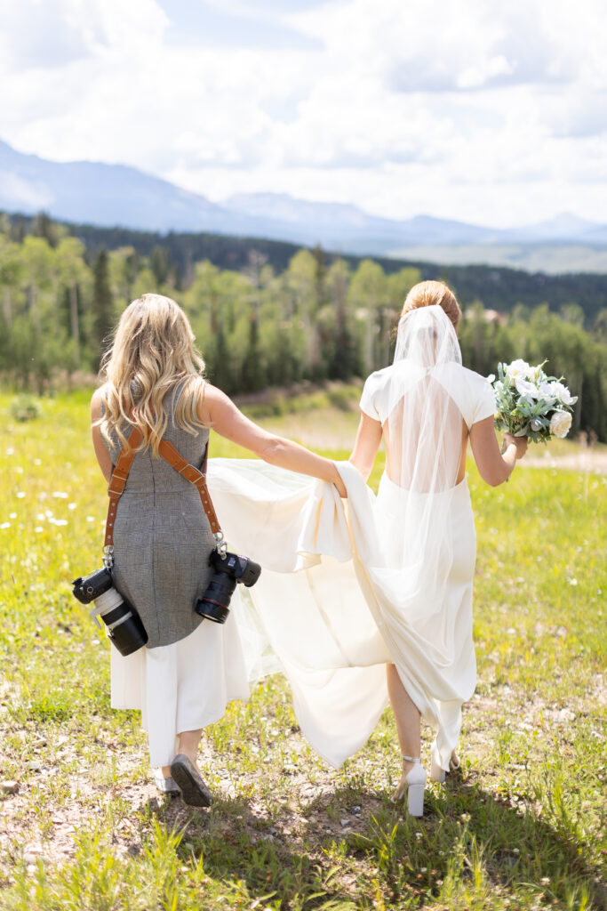 Lisa Marie Wright, a wedding photographer based in Telluride, CO, carries the back of a bride's wedding dress on her wedding day.
